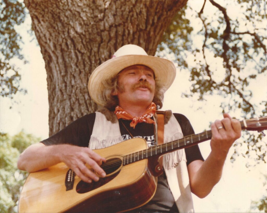 Frank playing and singing by big tree